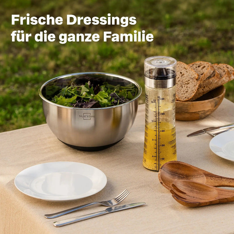 Silberthal glazen dressingmixer met dressing op een gedekte tuintafel naast een schaal salade.