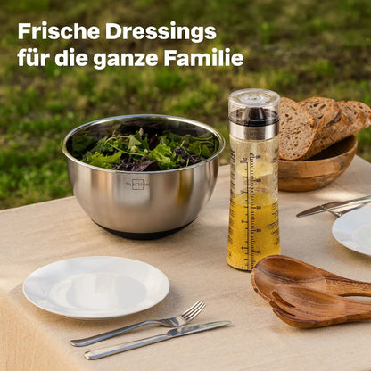 Silberthal glazen dressingmixer met dressing op een gedekte tuintafel naast een schaal salade.