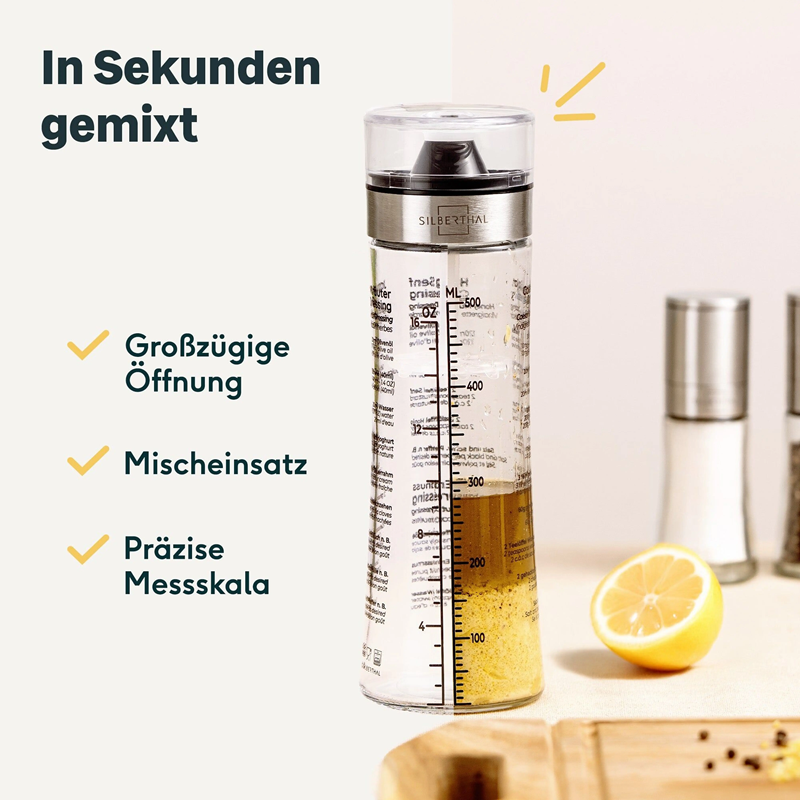 Glazen SILBERTHAL dressingshaker met maatverdeling tot 500 ml, roestvrijstalen rand en transparante dop, gevuld met dressing naast een halve citroen.